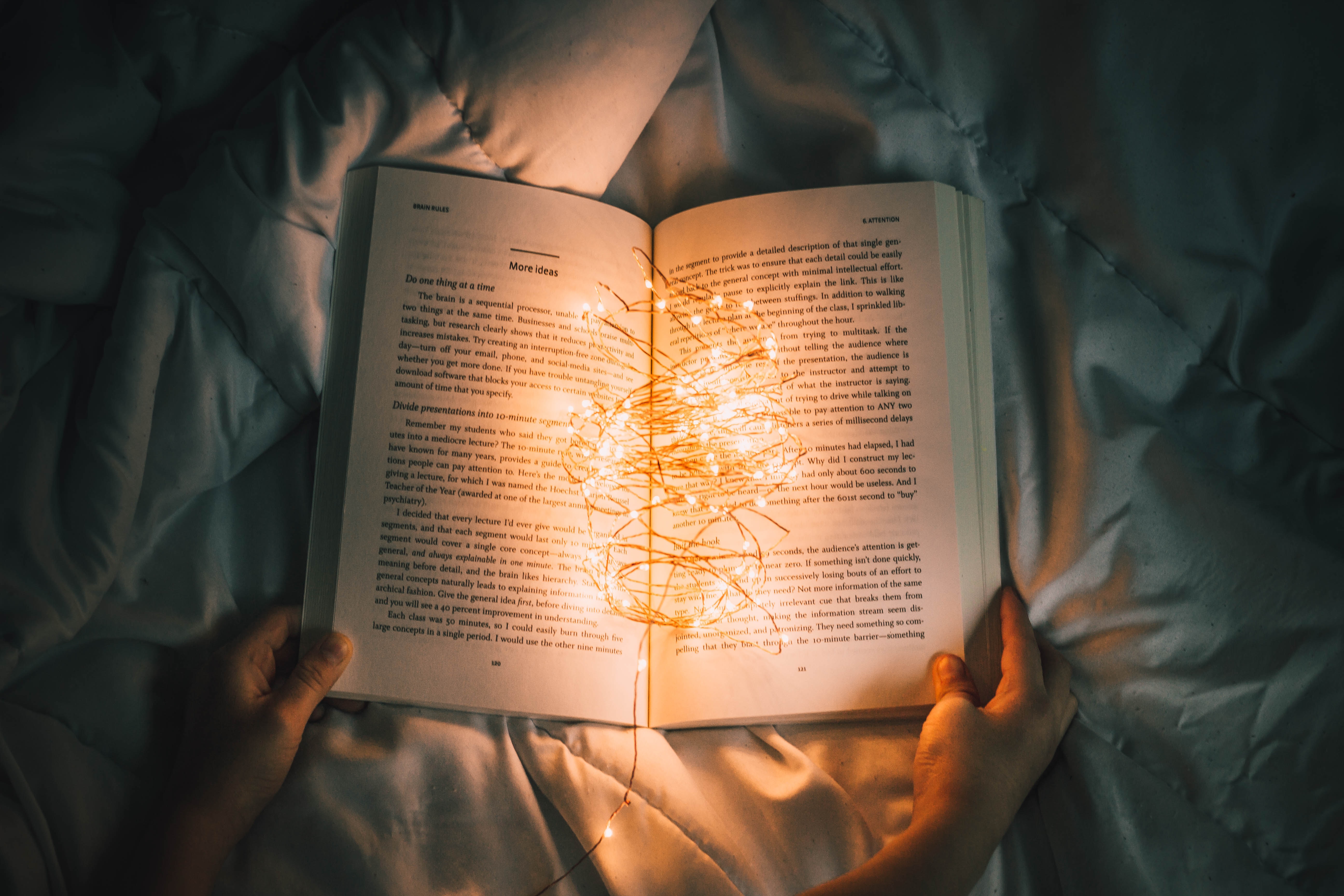 a person holding a book with a string of lights coming out of it